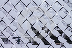 Winter creative background image. Snow, lying on mesh cells of chain-link