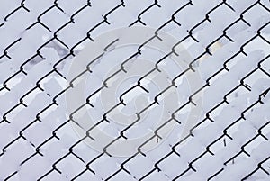 Winter creative background image. Snow, lying on mesh cells of chain-link