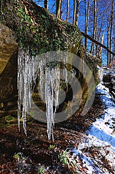 Winter creek with icicles above freeze mountain stream