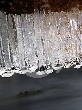 Winter creek with icicles above freeze mountain stream. Winter season