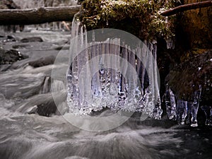 Winter creek with icicles above freeze mountain stream. Winter season