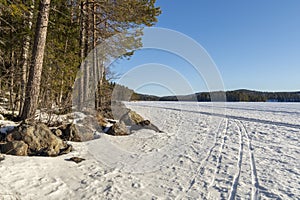 Winter day on a frozen lake with ski tracks in the snow