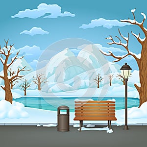 Winter day park. Snow covered wooden bench, trash bin and street lamp with frozen lake and snowy mountains.