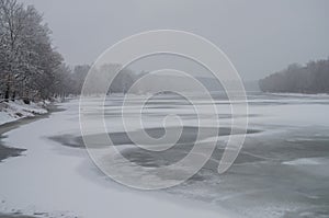 Winter day. River frozen - covered with ice and naked trees covered with white snow on there branches. Walking on nature