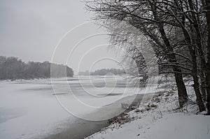 Winter day. River frozen - covered with ice and naked trees covered with white snow on there branches. Walking on nature