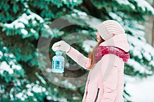 Winter day. Woman holding Christmas lantern outdoors on beautiful winter snow day