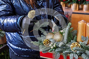 Winter decor. Florist at wort at the time of creating a beautiful Christmas decorations from natural spruce branches, golden
