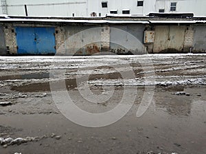 Winter dirty broken road in a garage cooperative. Gray depressing moody winter