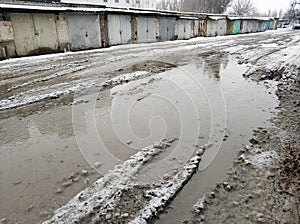 Winter dirty broken road in a garage cooperative. Gray depressing moody winter