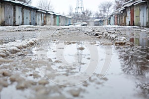 Winter dirty broken road in a garage cooperative. Gray depressing moody winter