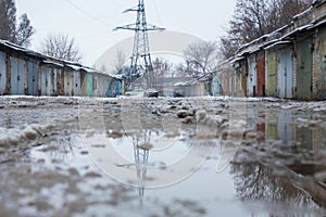 Winter dirty broken road in a garage cooperative. Gray depressing moody winter