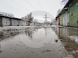 Winter dirty broken road in a garage cooperative. Gray depressing moody winter