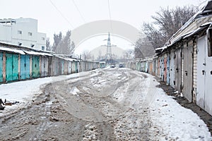 Winter dirty broken road in a garage cooperative. Gray depressing moody winter