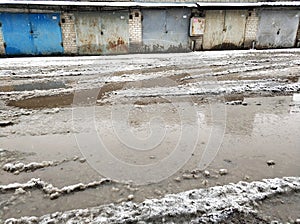 Winter dirty broken road in a garage cooperative. Gray depressing moody winter