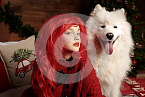 Winter dog holiday and Christmas. A girl in a knitted sweater and with red hair with a pet in the studio. Christmas