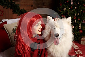 Winter dog holiday and Christmas. A girl in a knitted sweater and with red hair with a pet in the studio. Christmas