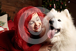 Winter dog holiday and Christmas. A girl in a knitted sweater and with red hair with a pet in the studio. Christmas