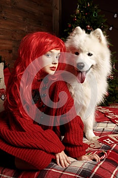 Winter dog holiday and Christmas. A girl in a knitted sweater and with red hair with a pet in the studio. Christmas