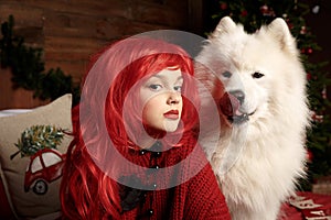 Winter dog holiday and Christmas. A girl in a knitted sweater and with red hair with a pet in the studio. Christmas