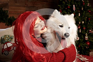 Winter dog holiday and Christmas. A girl in a knitted sweater and with red hair with a pet in the studio. Christmas