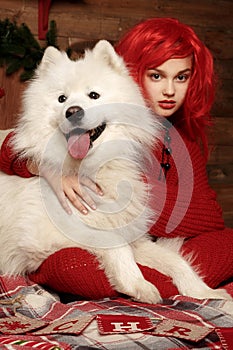 Winter dog holiday and Christmas. A girl in a knitted sweater and with red hair with a pet in the studio. Christmas