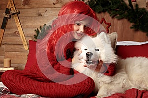 Winter dog holiday and Christmas. A girl in a knitted sweater and with red hair with a pet in the studio. Christmas