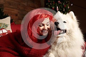 Winter dog holiday and Christmas. A girl in a knitted sweater and with red hair with a pet in the studio. Christmas