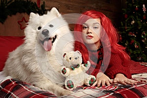 Winter dog holiday and Christmas. A girl in a knitted sweater and with red hair with a pet in the studio. Christmas
