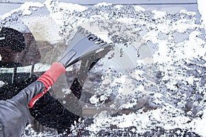 Winter driving. Hand of man is scraping ice and snow.