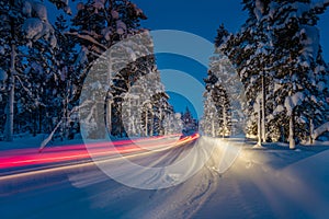 Winter Driving - Lights of car and winter road in forest at nigh