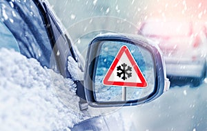 Winter driving - warning sign - risk of snow and ice. Winter driving - caution. Black Ice. Concept of snow in the road. Car hit a