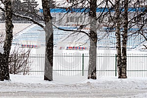 Winter empty stadium. Football field and seats for the teams spectators covered with snow. Sports seasons.