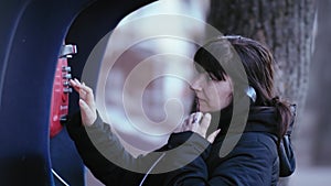 Winter Evening Connection: Woman Making a Payphone Call