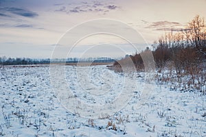 Winter evening in snowy fields of Russian province