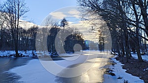 In winter, everything is covered with snow. The water channel in the city park is covered with ice. Trees are growing along the ba