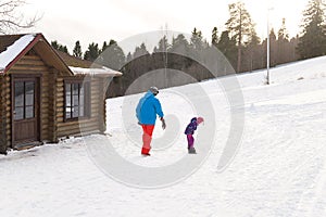 Winter extreme sport. Father is teaching his little daughter snowboarding on a snow slope