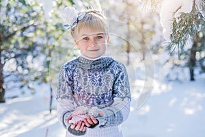 Winter fairy tale. Beautiful little girl is walking in a snowy forest