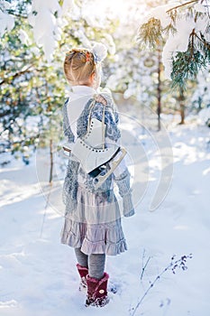 Winter fairy tale. Beautiful little girl is walking in a snowy forest