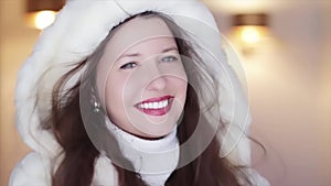 Winter fashion and Christmas holiday look. Beautiful smiling woman wearing white sweater and fluffy fur coat with hood