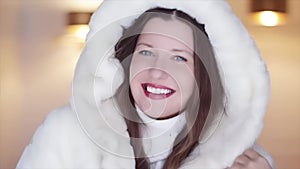 Winter fashion and Christmas holiday look. Beautiful smiling woman wearing white sweater and fluffy fur coat with hood