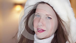 Winter fashion and Christmas holiday look. Beautiful smiling woman wearing white sweater and fluffy fur coat with hood