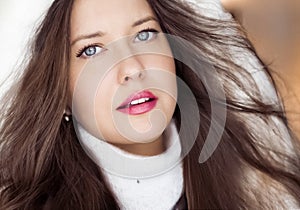 Winter fashion and Christmas holiday look. Beautiful woman wearing white sweater and fluffy fur coat with hood wrap