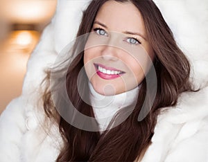 Winter fashion and Christmas holiday look. Beautiful woman wearing white sweater and fluffy fur coat with hood wrap