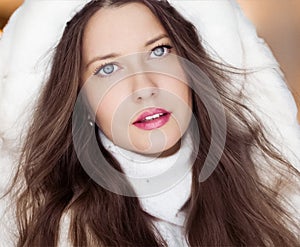 Winter fashion and Christmas holiday look. Beautiful woman wearing white sweater and fluffy fur coat with hood wrap