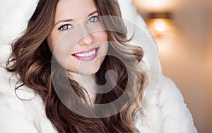 Winter fashion and Christmas holiday look. Beautiful woman wearing white sweater and fluffy fur coat with hood wrap