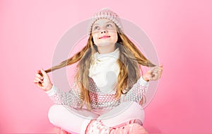 Winter fashion concept. Girl long hair relaxing pink background. Kid smiling fashion model. Kid girl wear cute knitted