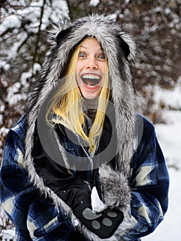 Winter fashion. Happy woman in warm clothing with snowball. Smiling girl in mittens, warm plaid coat and fur hat playing