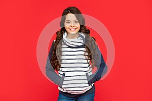 winter fashion. positive kid with curly hair in fleece jacket. teen girl on red background.