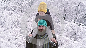 Winter father and son piggyback ride outdoor in snow forest. Dad play with child snow ball fight.