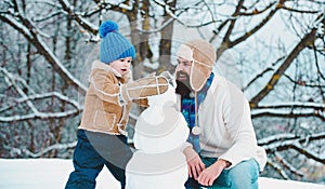 Winter, father and son play outdoo making snowman. Handmade funny snow man. Christmas family holidays with daddy.